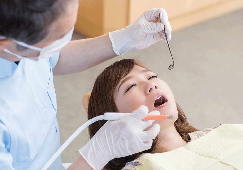 目を閉じて歯科治療を受ける女性